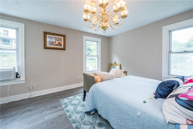 bedroom with a chandelier, cooling unit, wood finished floors, and baseboards