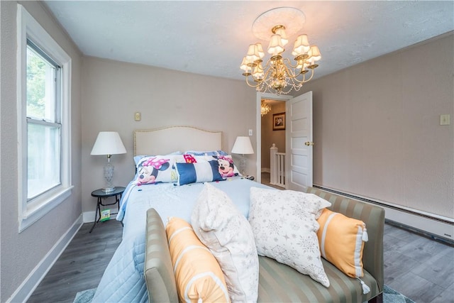 bedroom with a notable chandelier, baseboards, and wood finished floors