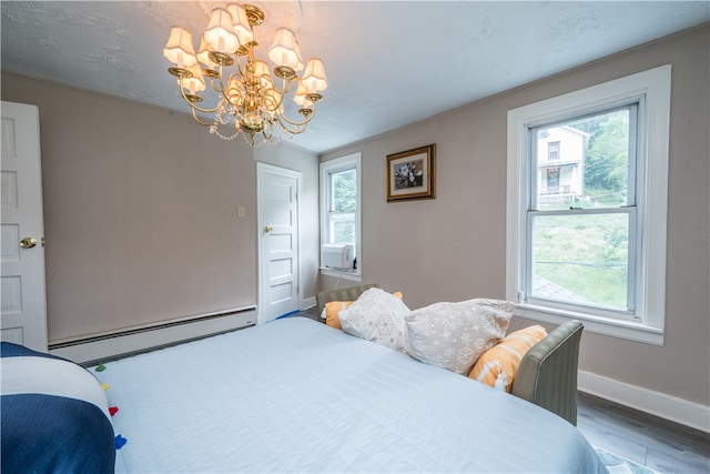 bedroom with multiple windows, hardwood / wood-style floors, a chandelier, and a baseboard radiator