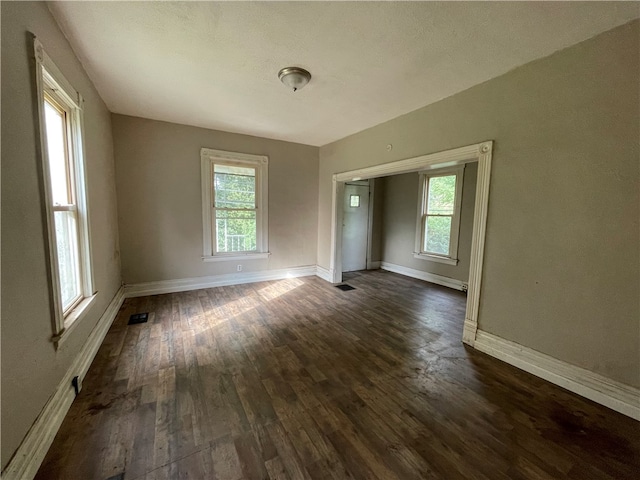 unfurnished room with a wealth of natural light and dark hardwood / wood-style floors