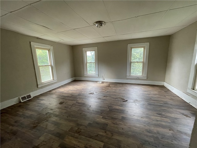 unfurnished room featuring dark wood-type flooring and a paneled ceiling