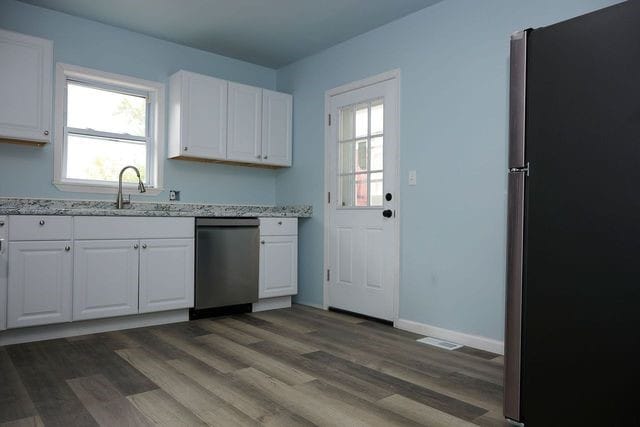 kitchen featuring sink, dark hardwood / wood-style flooring, appliances with stainless steel finishes, light stone countertops, and white cabinets