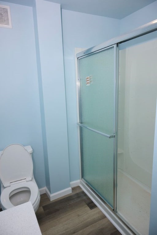 bathroom featuring hardwood / wood-style flooring, toilet, and walk in shower