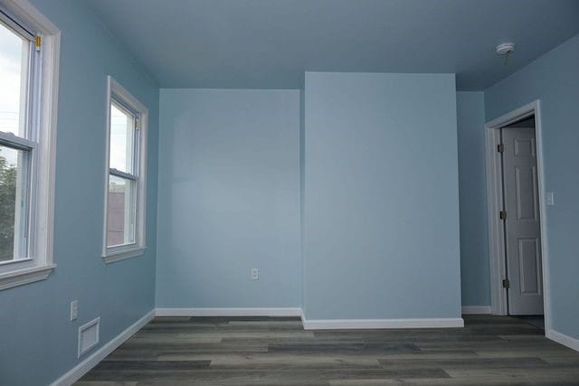 unfurnished room with dark wood-type flooring