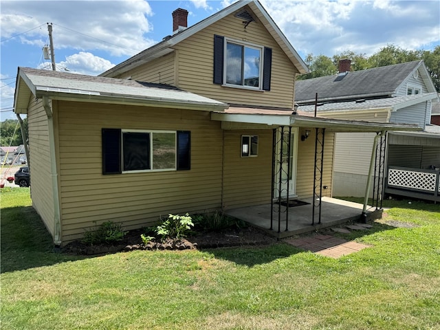 back of house featuring a patio area and a lawn