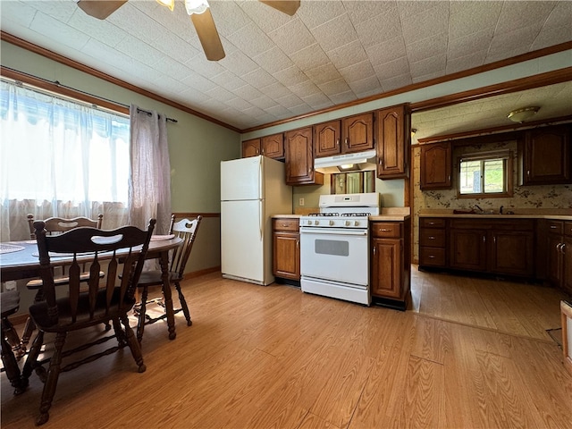 kitchen with white appliances, ceiling fan, wall chimney range hood, and light hardwood / wood-style flooring