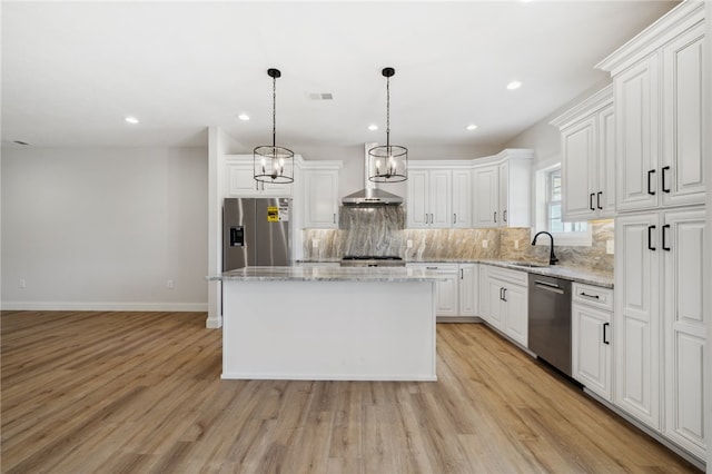 kitchen featuring stainless steel appliances, white cabinetry, wall chimney exhaust hood, light hardwood / wood-style flooring, and a center island