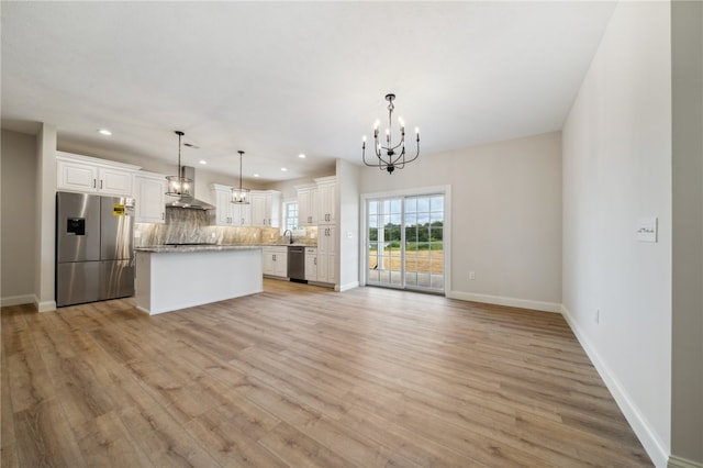 kitchen with white cabinets, a kitchen island, decorative light fixtures, and appliances with stainless steel finishes