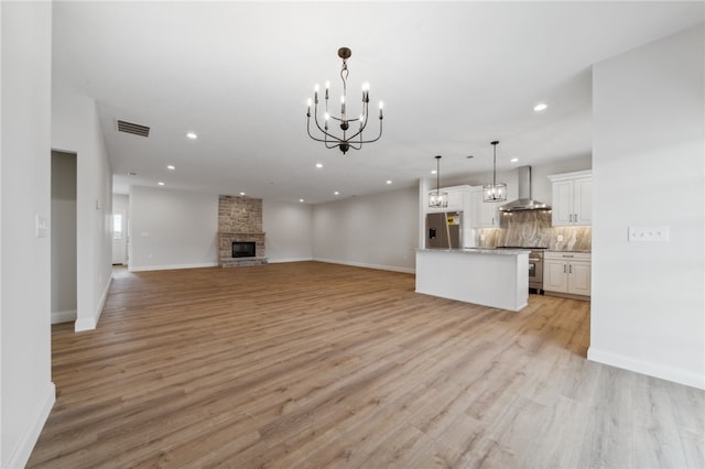 unfurnished living room featuring a stone fireplace and light wood-type flooring