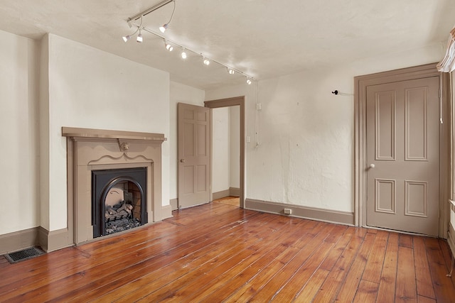 unfurnished living room with hardwood / wood-style flooring and rail lighting