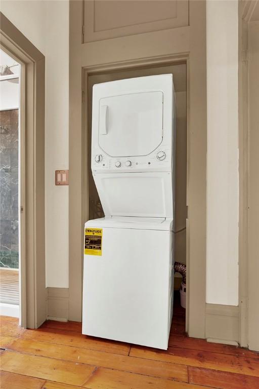 laundry room featuring light hardwood / wood-style floors and stacked washer and clothes dryer