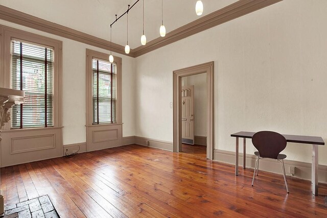 unfurnished dining area featuring hardwood / wood-style flooring, track lighting, and crown molding