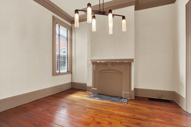 unfurnished living room featuring hardwood / wood-style floors and crown molding