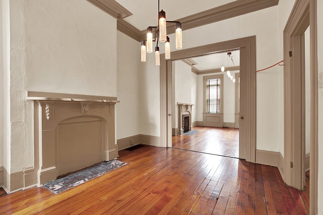 unfurnished living room with a notable chandelier, hardwood / wood-style floors, and ornamental molding