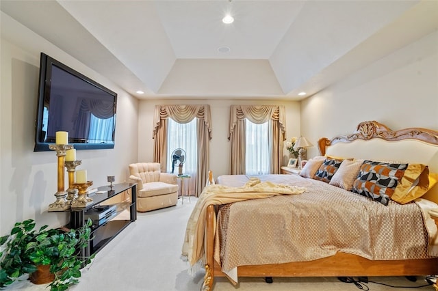 bedroom with light colored carpet and a tray ceiling