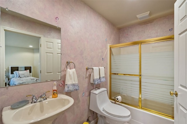 full bathroom featuring sink, bath / shower combo with glass door, and toilet