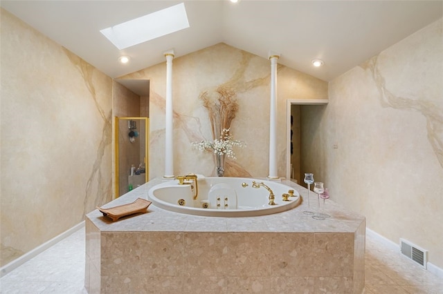 bathroom featuring tiled bath, vaulted ceiling with skylight, and tile patterned flooring