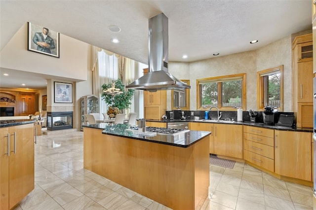 kitchen with a center island, a tiled fireplace, island range hood, and light tile patterned floors