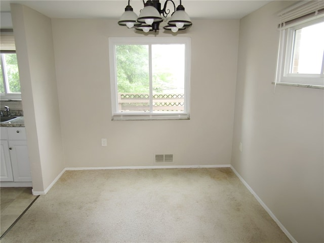 unfurnished dining area featuring light colored carpet, an inviting chandelier, and sink