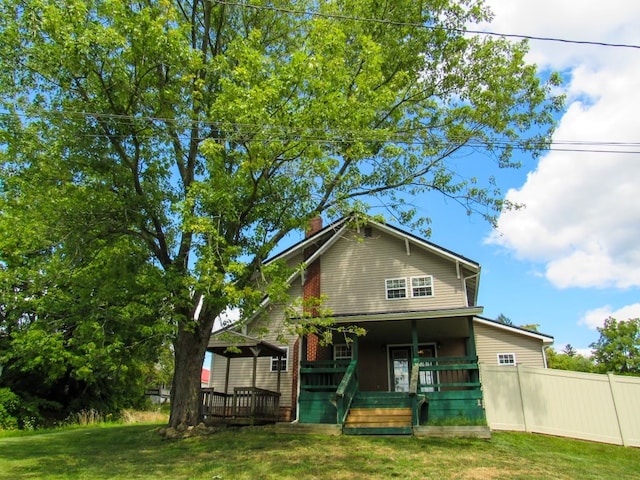 rear view of house featuring a porch and a lawn