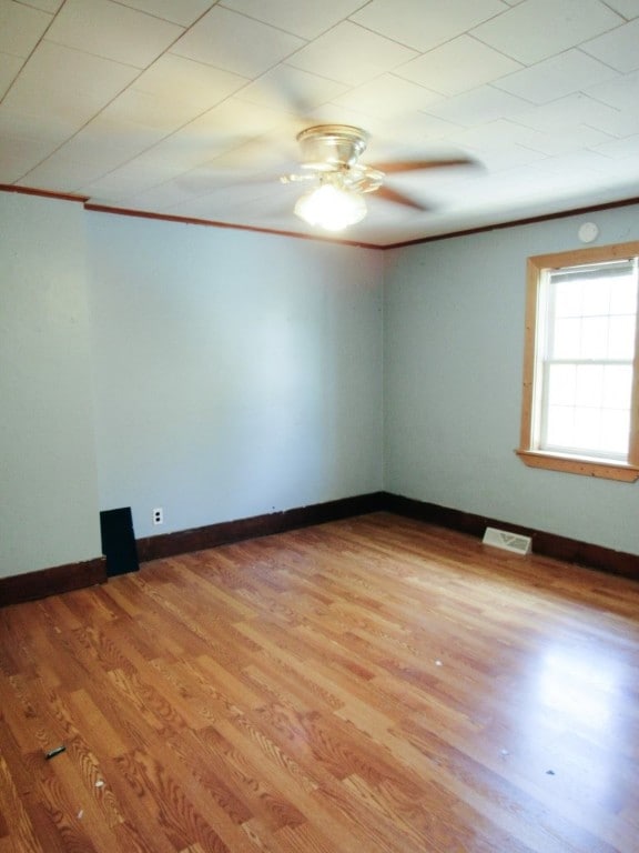 unfurnished room with ceiling fan, crown molding, and wood-type flooring