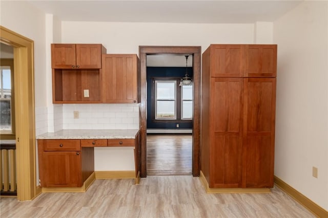 kitchen featuring light wood-style flooring, a baseboard heating unit, brown cabinetry, decorative backsplash, and radiator heating unit