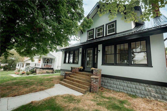 view of front of home featuring a standing seam roof, a porch, metal roof, and stucco siding