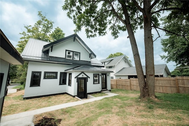 back of property with metal roof, fence, a yard, stucco siding, and a standing seam roof