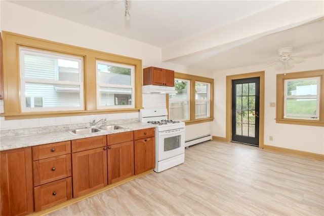 kitchen featuring white gas range oven, brown cabinets, under cabinet range hood, a baseboard heating unit, and a sink