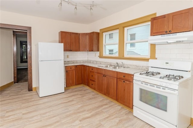 kitchen featuring white appliances, brown cabinets, a sink, and under cabinet range hood