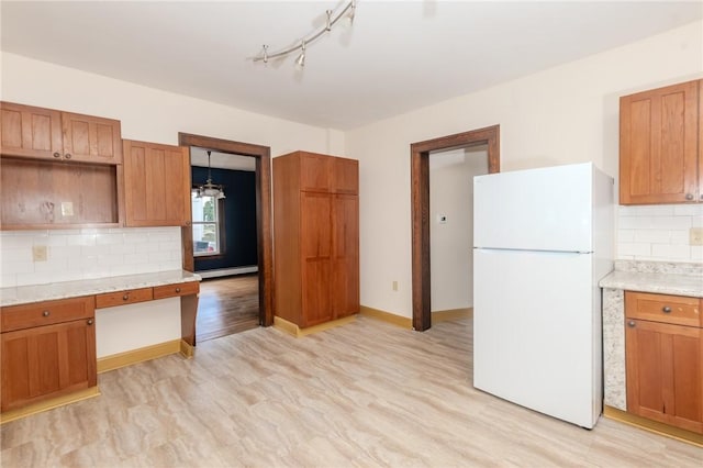 kitchen with light wood finished floors, tasteful backsplash, brown cabinetry, freestanding refrigerator, and baseboard heating