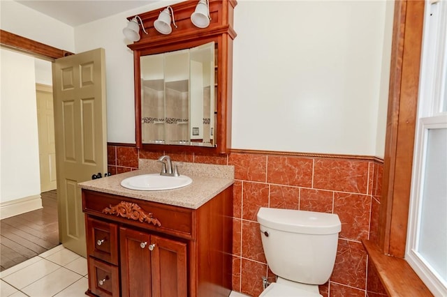 bathroom featuring a wainscoted wall, vanity, toilet, and tile walls