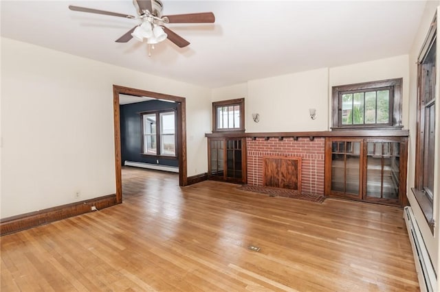 unfurnished living room with light wood-style floors, a fireplace, and baseboard heating