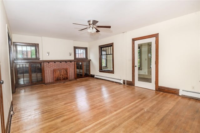 unfurnished living room with light wood-type flooring, a fireplace, a baseboard heating unit, and a ceiling fan