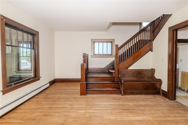 staircase with radiator, baseboards, a baseboard heating unit, and wood finished floors