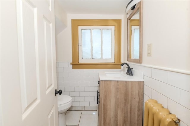 half bathroom featuring a wainscoted wall, radiator heating unit, tile walls, and tile patterned floors