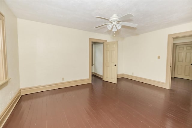 empty room with dark wood-style floors, ceiling fan, and baseboards