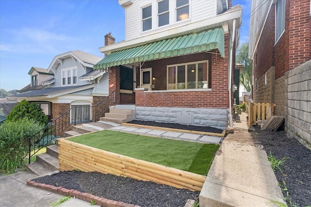 view of front of house featuring fence, a porch, and brick siding