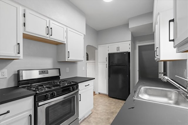 kitchen with white cabinets, light tile patterned flooring, black refrigerator, and gas stove