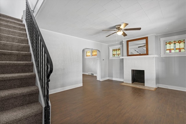 unfurnished living room featuring ceiling fan, crown molding, wood-type flooring, and a brick fireplace