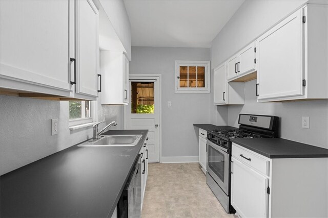 kitchen featuring light tile patterned floors, gas range, sink, and white cabinets