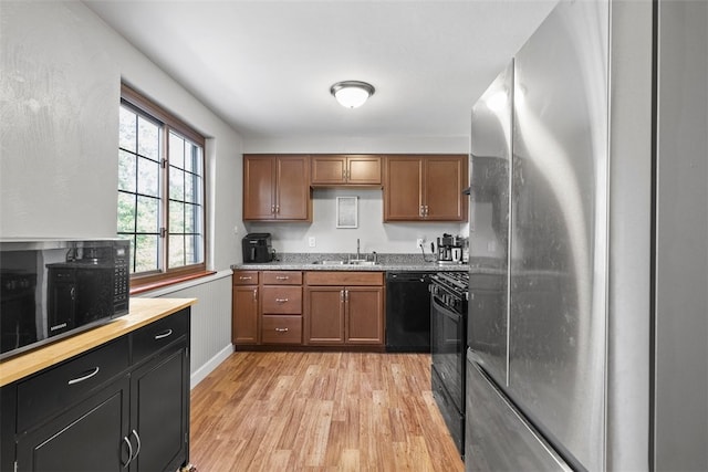 kitchen with sink, black appliances, and light hardwood / wood-style flooring