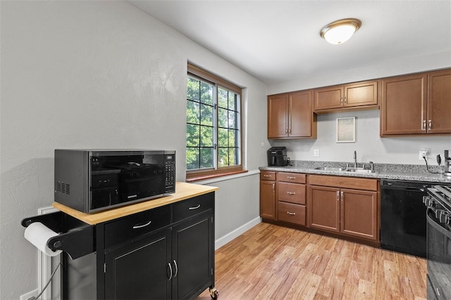 kitchen with light hardwood / wood-style flooring, black dishwasher, light stone counters, sink, and stove