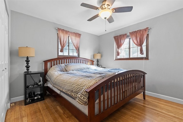 bedroom with a closet, ceiling fan, hardwood / wood-style floors, and multiple windows