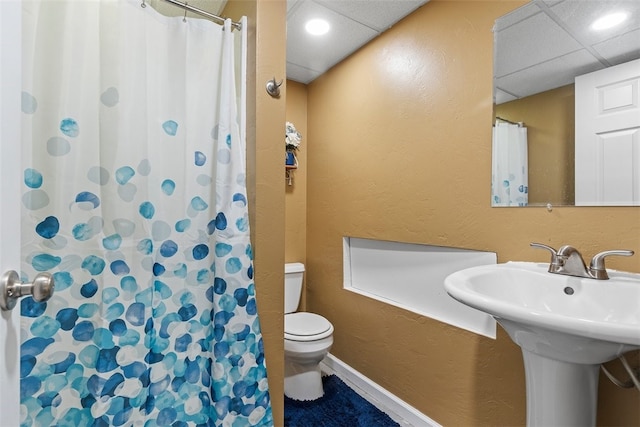 bathroom with a drop ceiling, toilet, and curtained shower