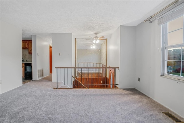 carpeted empty room featuring ceiling fan and a textured ceiling