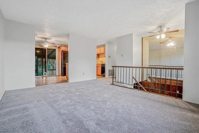 empty room with a textured ceiling, carpet flooring, and ceiling fan