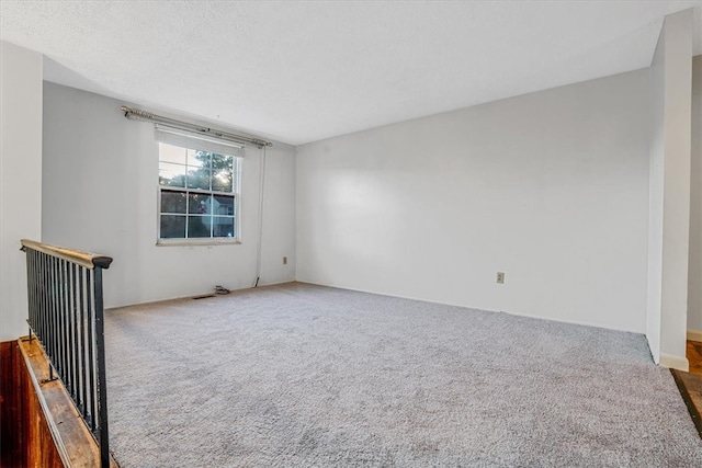 empty room featuring a textured ceiling and carpet