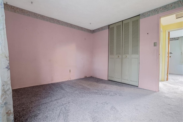 unfurnished bedroom featuring a closet and light carpet