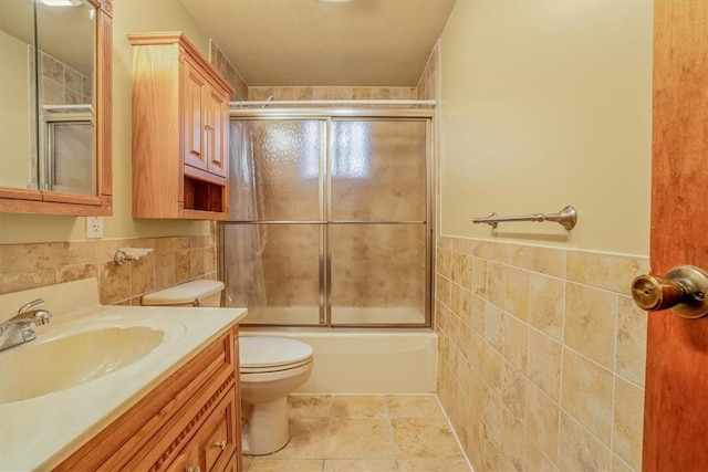 full bathroom featuring shower / bath combination with glass door, tile walls, toilet, vanity, and tile patterned floors